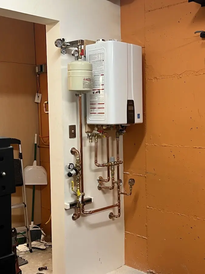 Plumbing technician inspecting water heater connections in Ludington